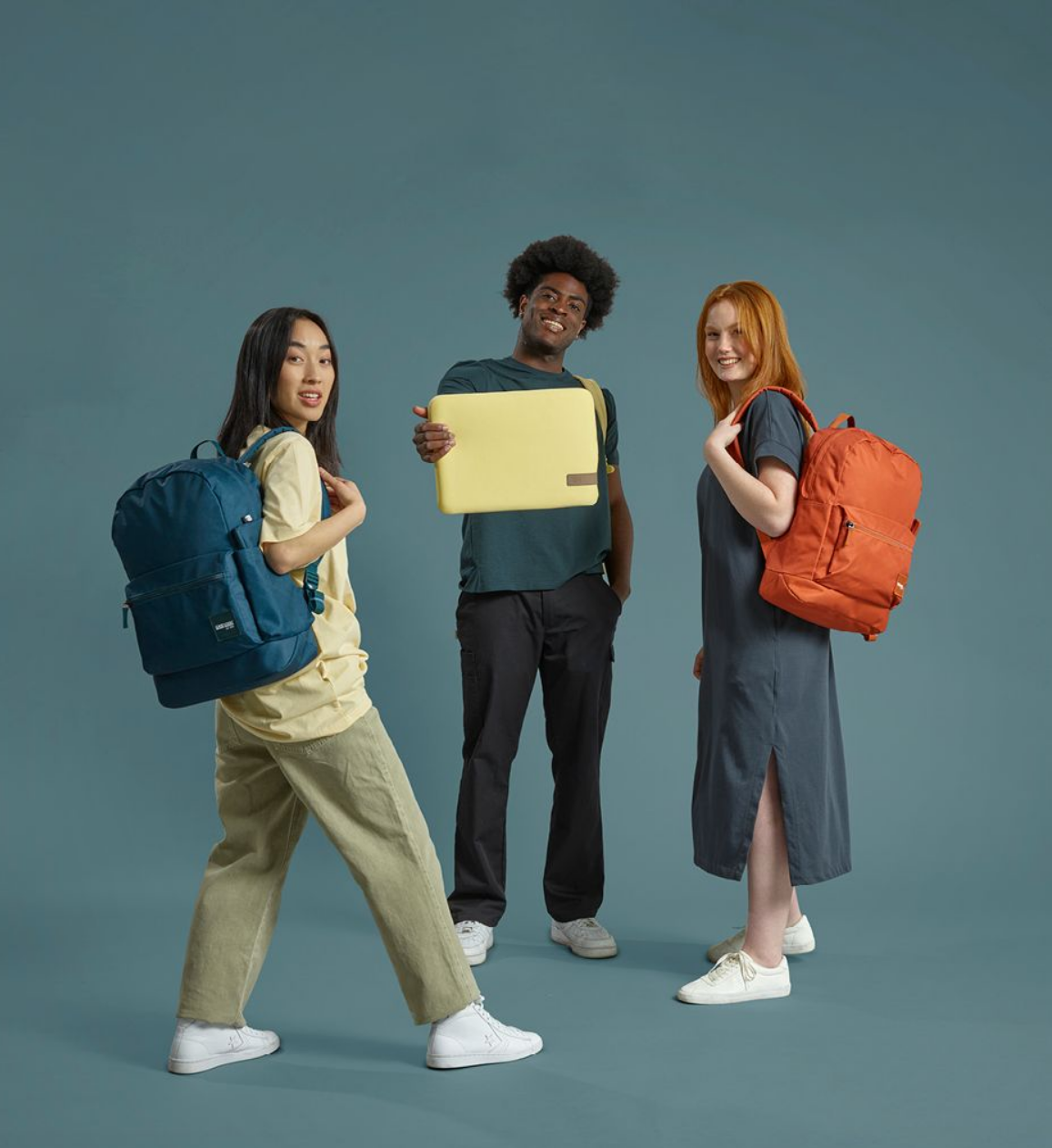 Three people standing in a circle, two have backpacks and one is holding a laptopsleeve.