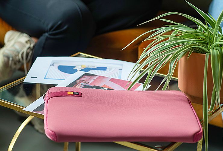 A close-up of a pink Case Logic laptop sleeve on a glass table.