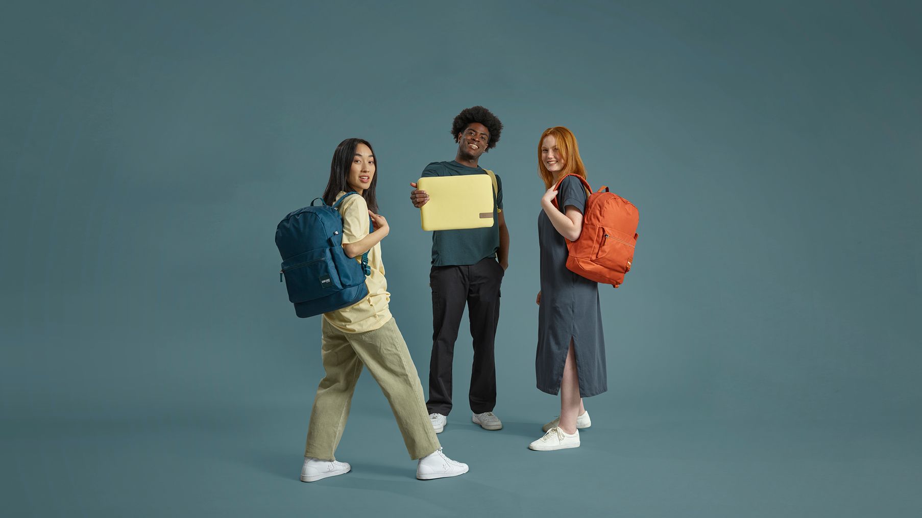 Three people standing in a circle, two have backpacks and one is holding a laptopsleeve.