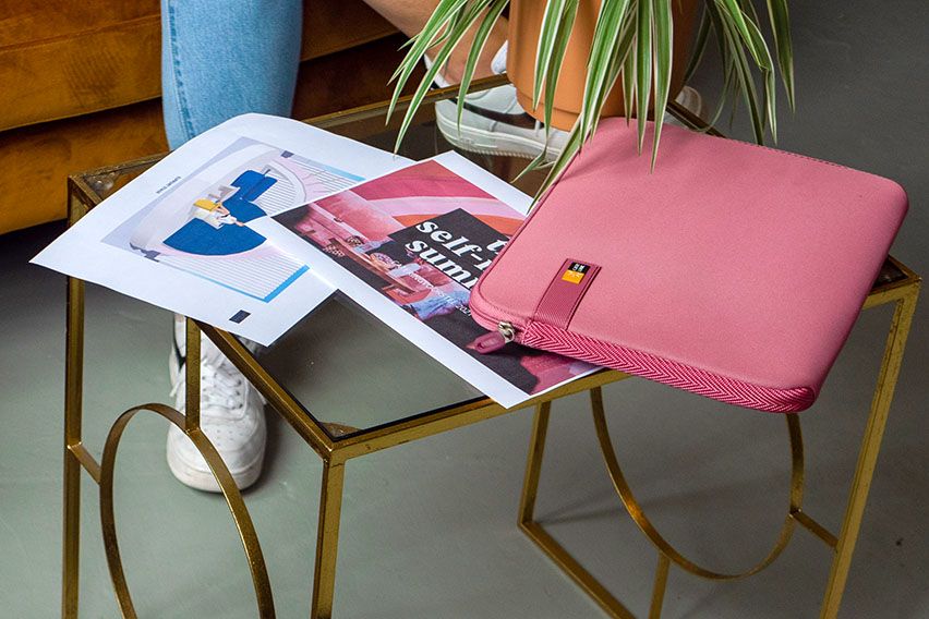 A close-up of a pink Case Logic laptop sleeve on a glass table.