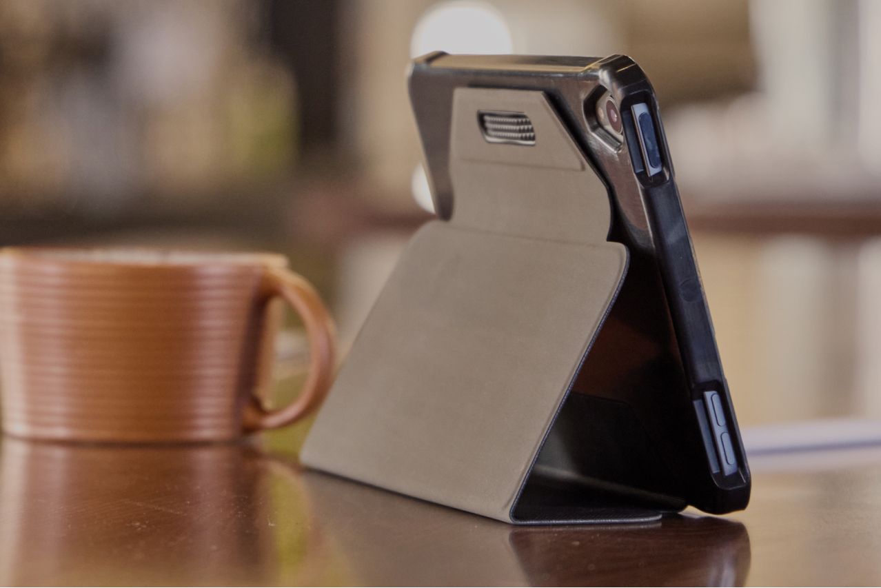 A close-up of a Case Logic tablet case holding up a tablet on a table with a coffee cup.