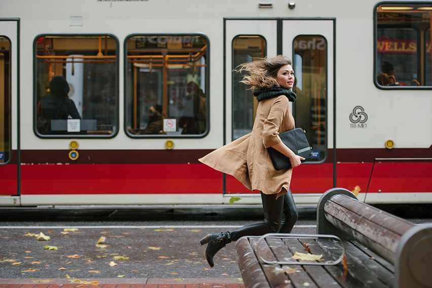 A woman rushes to take a tram while holding a Case Logic laptop sleeve.