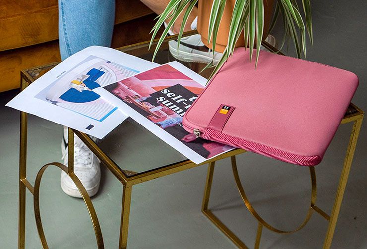 A close-up of a pink Case Logic laptop sleeve on a glass table.