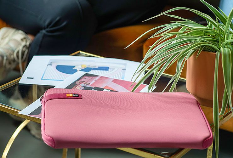 A close-up of a pink Case Logic laptop sleeve on a glass table.